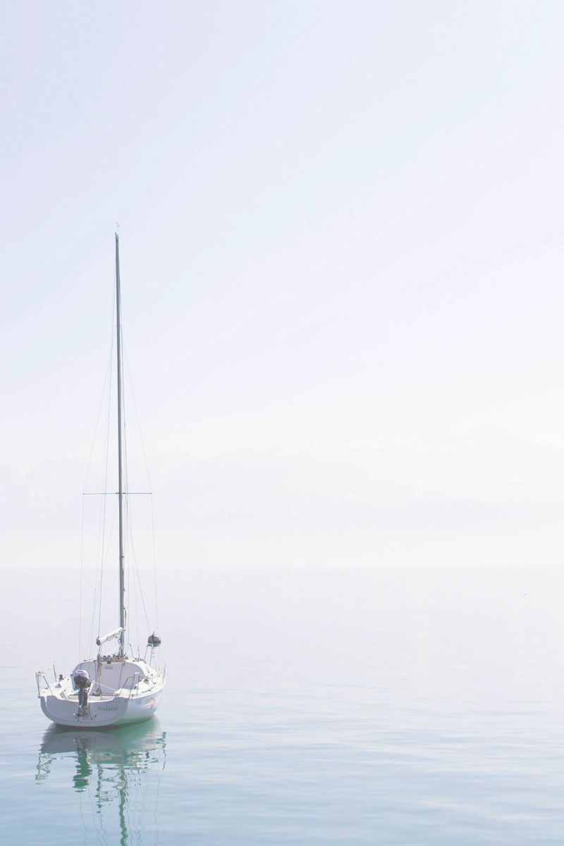 Tranquil-Counselling-By-Jill-Whitehills-Banff-Aberdeenshire-Person-Centred-Counselling A small white yacht drifts on a calm blue sea, the sky is cloudless.